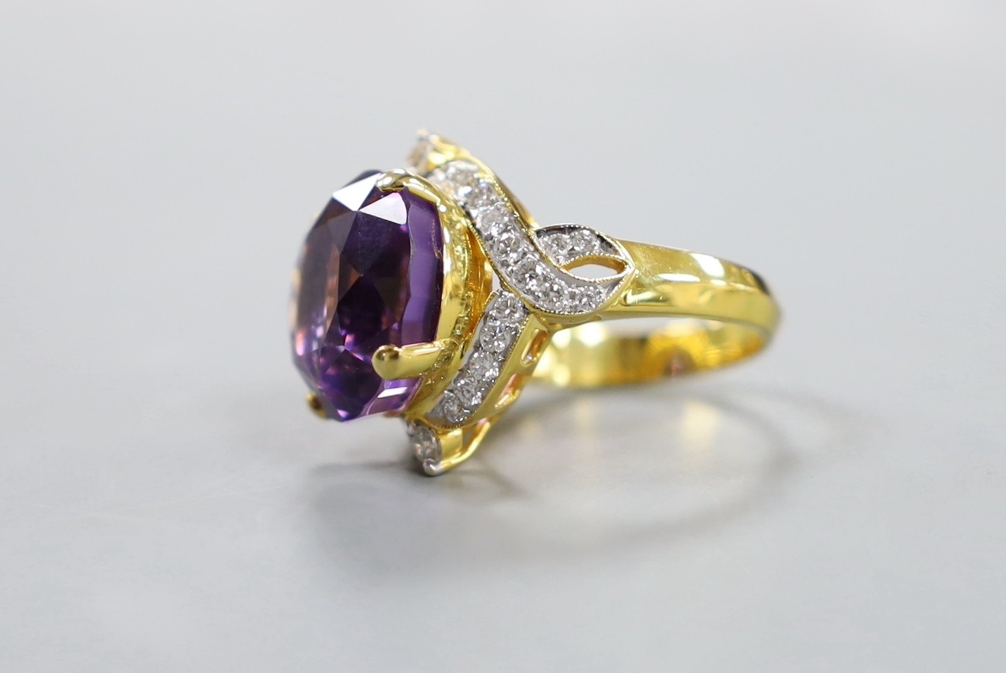 A modern yellow metal, round cut amethyst and diamond chip set cluster dress ring, size M, gross weight 10.9 grams.